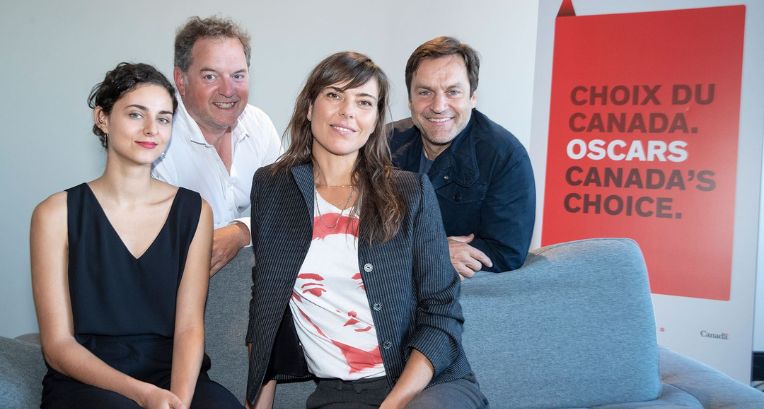 Actors Nahéma Ricci, Paul Doucet, and Benoît Gouin, alongside Sophie Deraspe, pose sitting on a couch next to a sign that reads "Choix du Canada. Oscars. Canada's Choice," at a press conference announcing Antigone, directed by Deraspe, as Canada's entry for the 92nd Academy Awards.